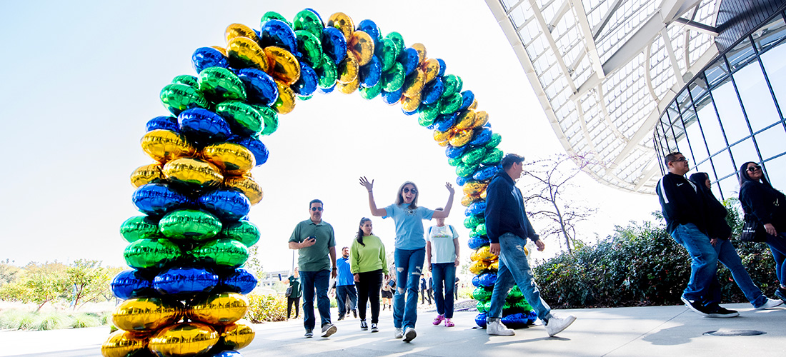 Female student walks through balloon arch